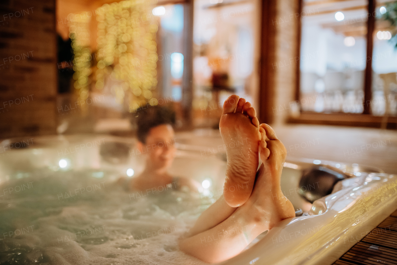 Young woman enjoying outdoor bathtub with her friend, in her terrace during a cold winter evening.