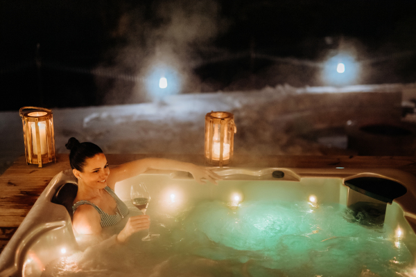 Young woman enjoying outdoor bathtub in her terrace during a cold winter evening.