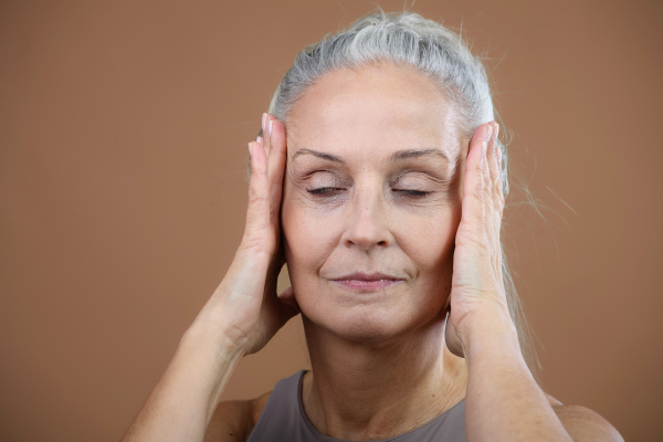 Portrait of smiling senior woman with closed eyes in a studio.