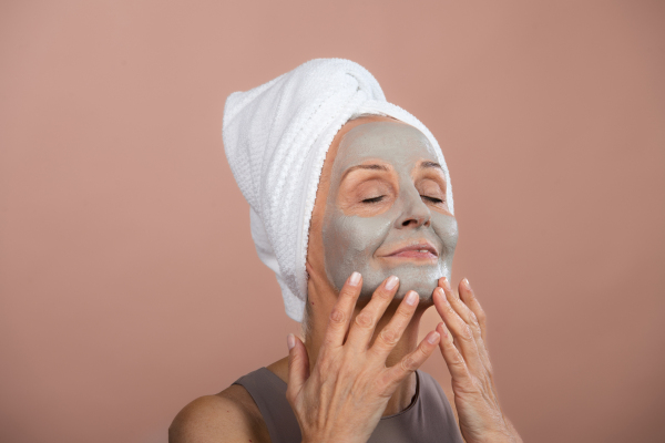 Portrait of excited senior woman with a face-mask, selfcare and skin routine concept.