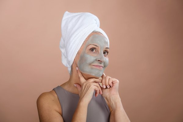 Portrait of excited senior woman with a face-mask, selfcare and skin routine concept.