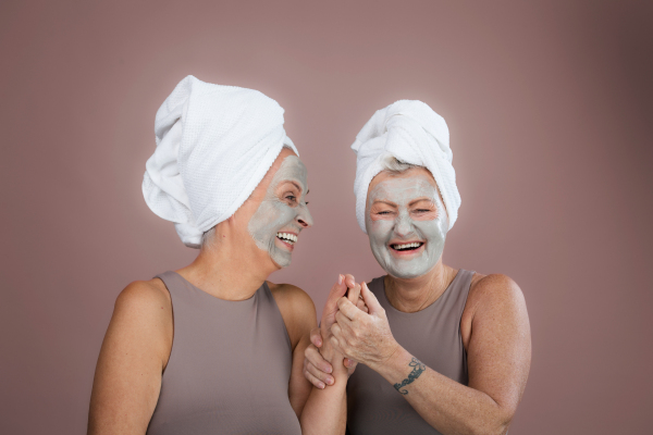 Portrait of happy senior friends with a face-mask, selfcare and skin routine concept.