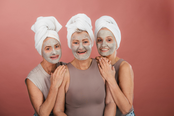 Portrait of happy senior friends with a face-mask, selfcare and skin routine concept.