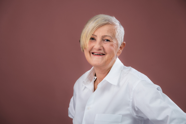 Portrait of elegant senior woman in a studio. Smiling elderly woman with short gray hair.