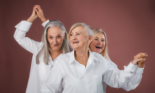 Portrait of three happy senior friends in a studio.