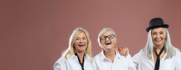 Portrait of three happy senior friends in a studio.