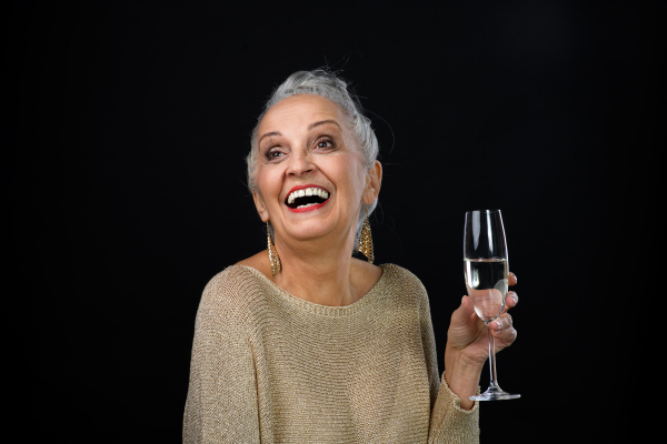 Portrait of happy senior woman with glass of wine, celebration concept.