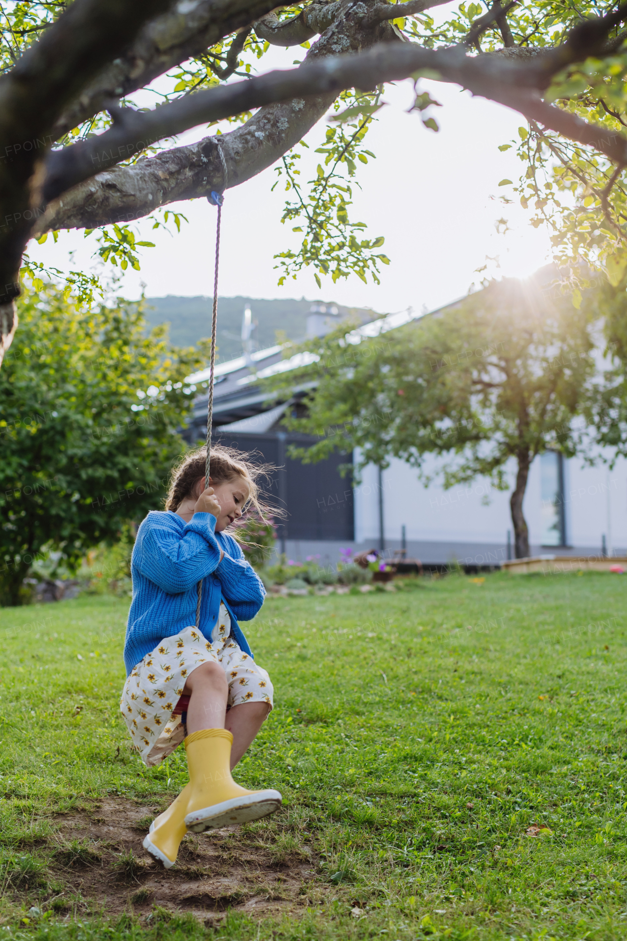 A young girl swinging on a swing in the garden. The schoolgirl spending free time with her grandparents in the garden on a warm autumn day.