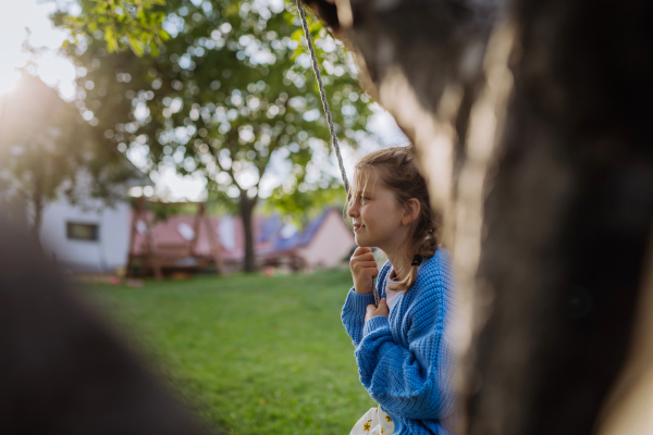 A young girl swinging on a swing in the garden. The schoolgirl spending free time with her grandparents in the garden on a warm autumn day.