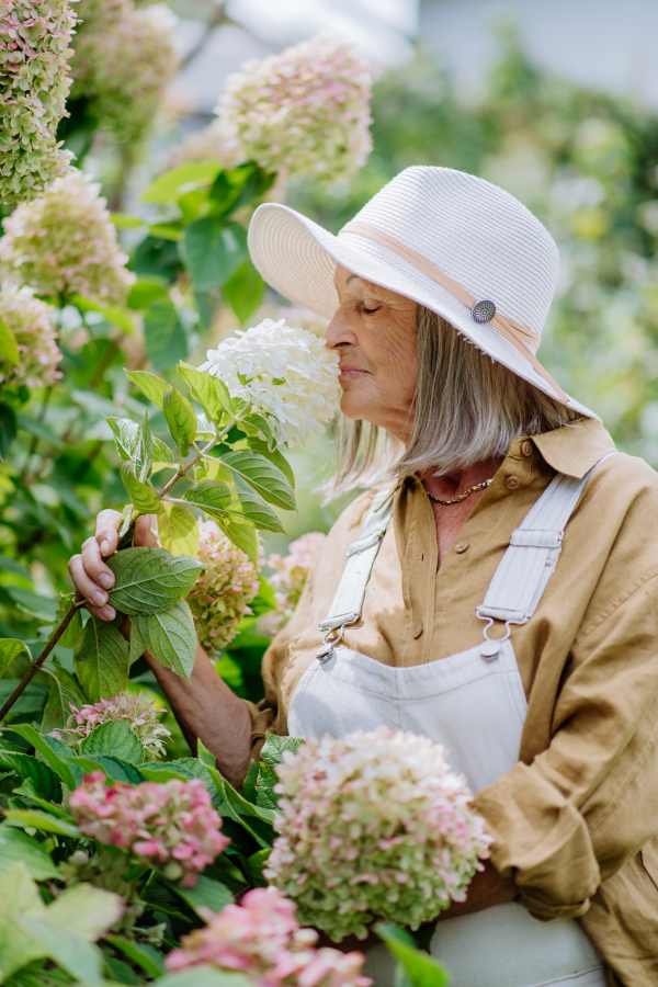 Happy senior woman posing in a flower garden.