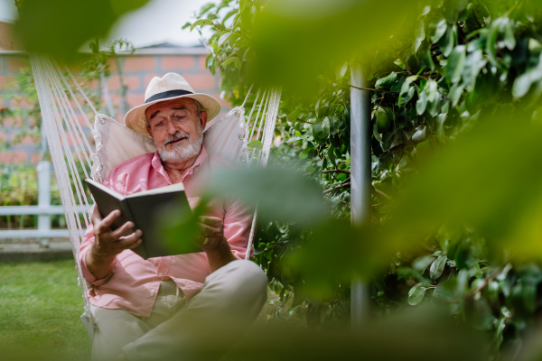 Happy senior man relaxing with book in the garden.