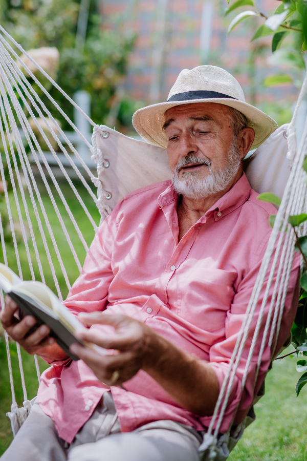 Happy senior man relaxing with book in the garden.