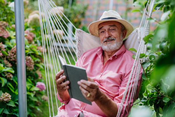 Happy senior man relaxing with book in the garden.