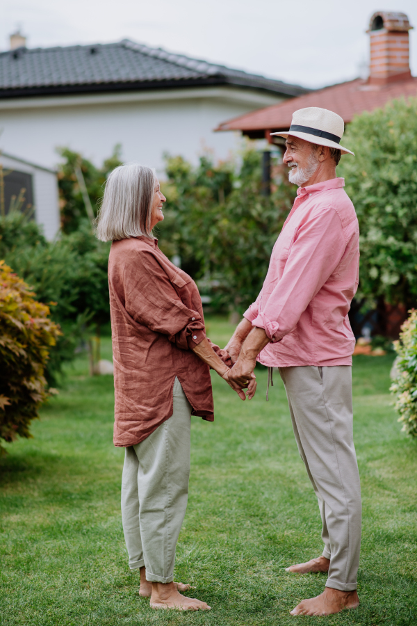 Senior couple in love posing together in a garden, holding each other hands.