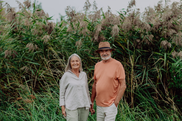 Happy senior couple on walk near the lake during cloudy autumn day.