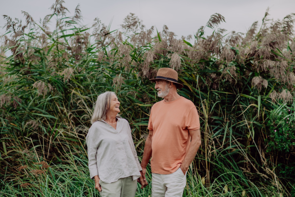 Happy senior couple on walk near the lake during cloudy autumn day.