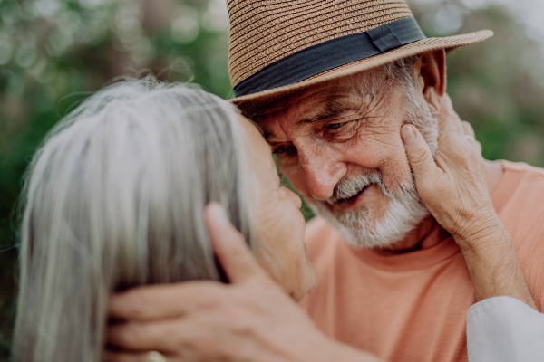 Portrait of senior couple in love, standing outdoor in the nature,stroking cheeks.