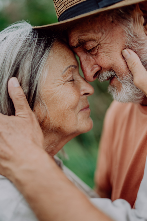 Portrait of senior couple in love, standing outdoor in the nature,stroking cheeks.