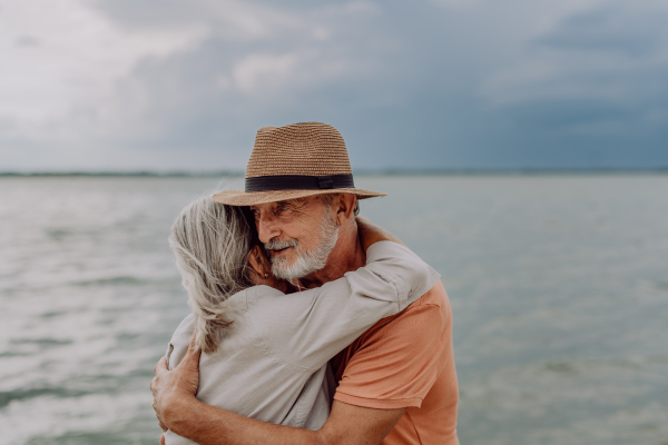 Senior couple in love embracing each other, having a romantic moment near the autumn sea.