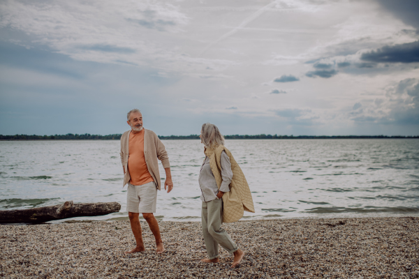 Senior couple walking near sea during an autumn day.