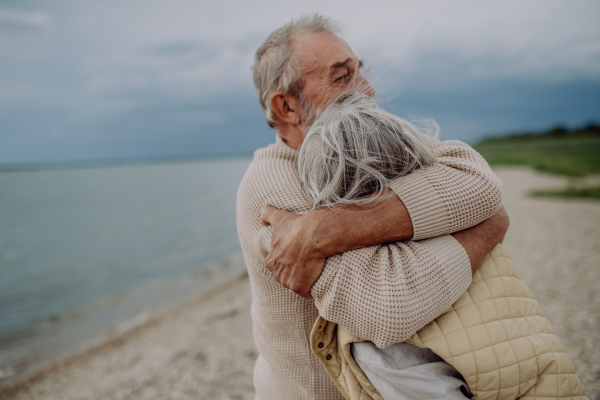 Senior couple in love embracing each other, having a romantic moment near the autumn sea.