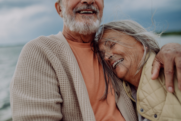 Senior couple sitting and having romantic moment at the autumn sea.