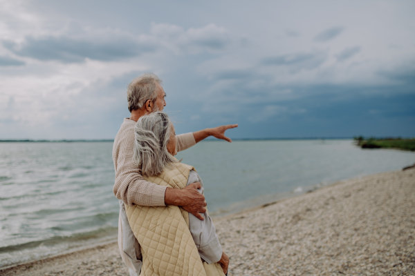 Senior couple relaxing and looking at autumn ocean.