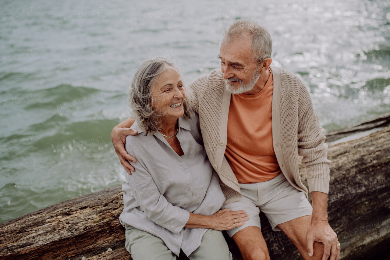 Senior couple sitting and having romantic moment at the autumn sea.