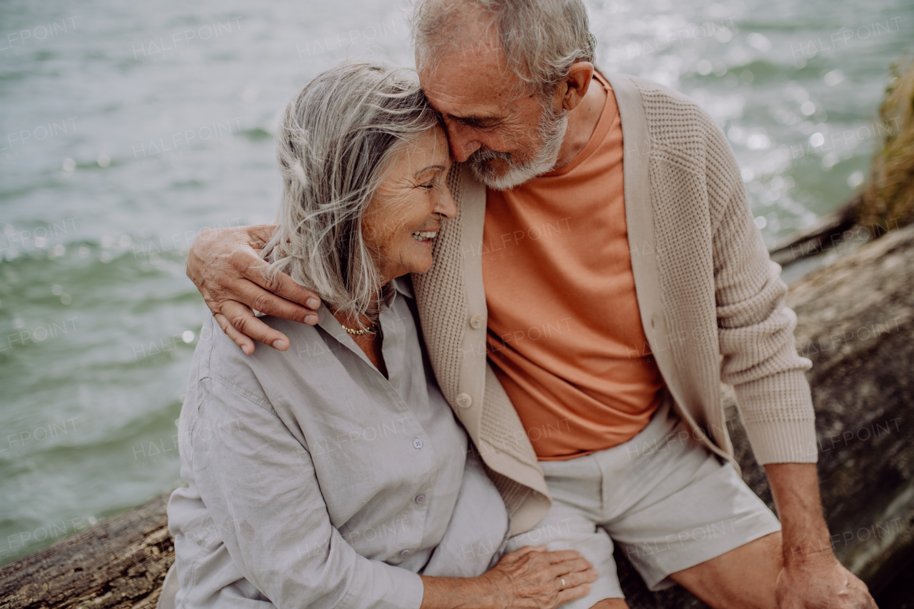 Senior couple sitting and having romantic moment at the autumn sea.