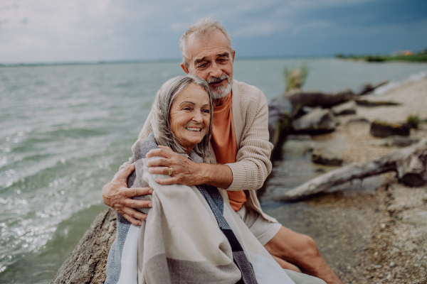 Senior couple sitting and having romantic moment at the autumn sea.