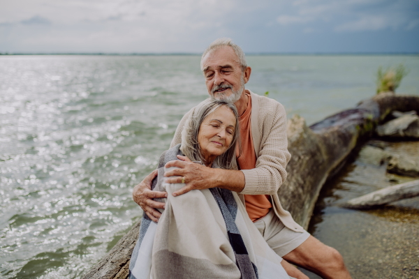 Senior couple sitting and having romantic moment at the autumn sea.