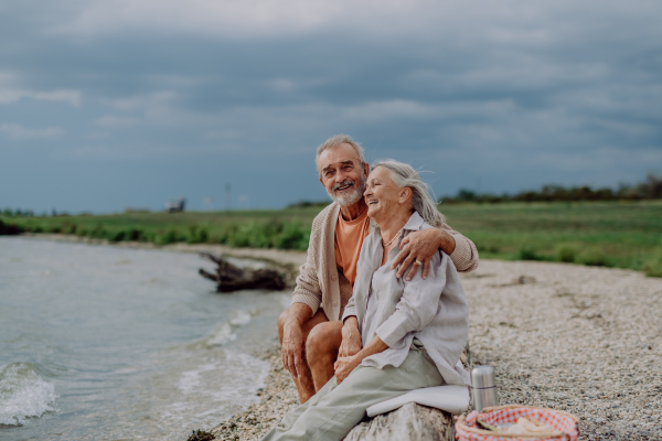 Senior couple sitting and having romantic moment at the autumn sea.