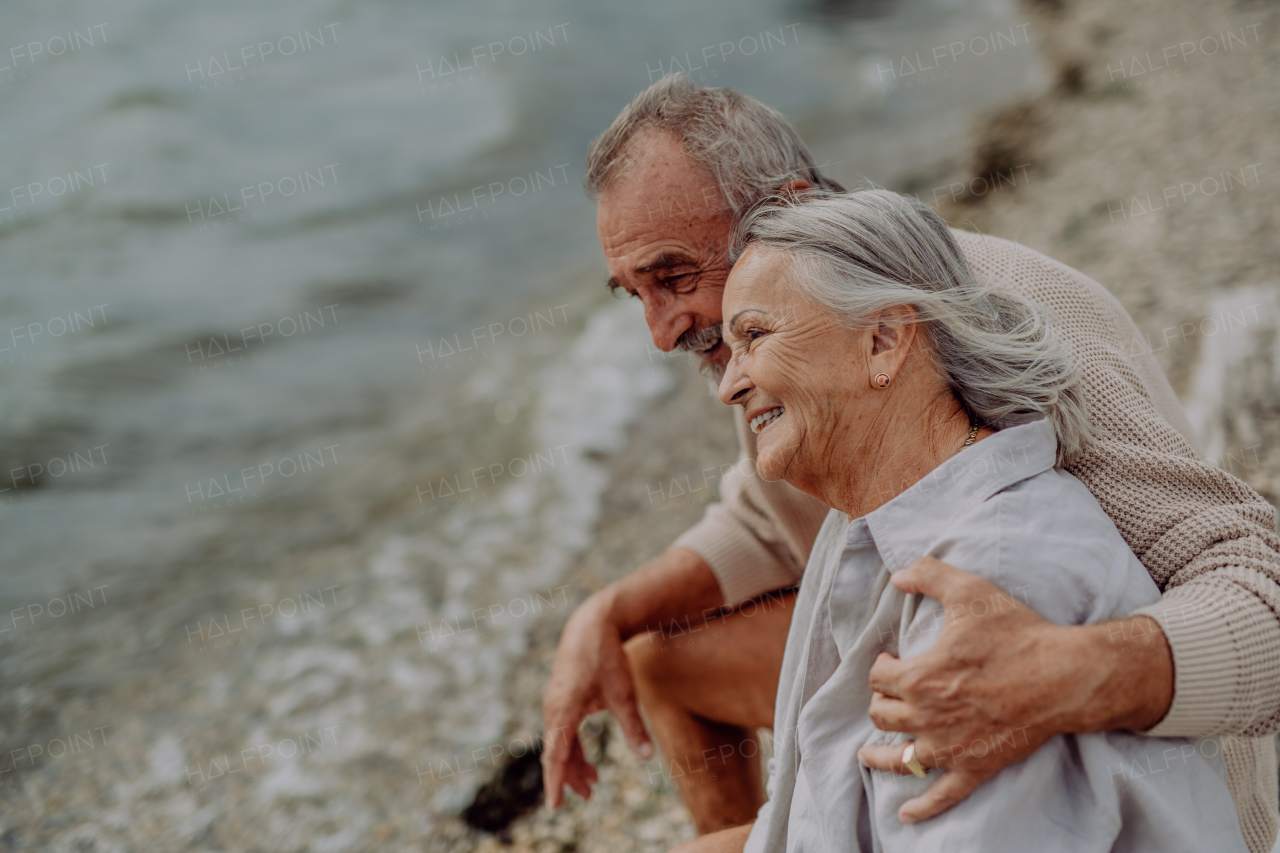 Senior couple sitting and having romantic moment at the autumn sea.