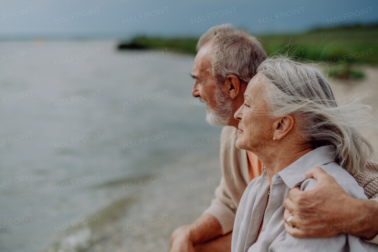 Senior couple relaxing and looking at autumn ocean.