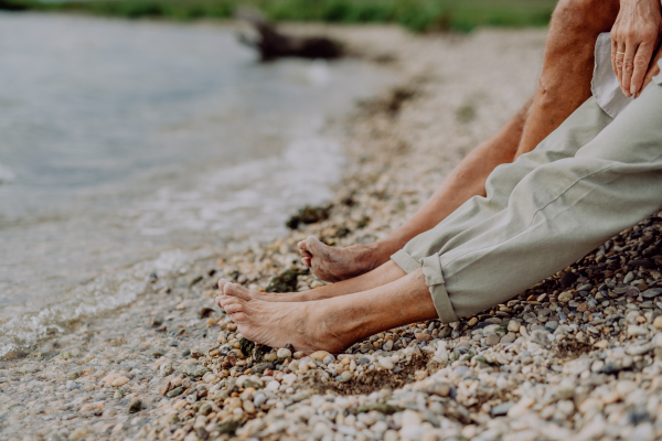 Close up seniors legs at beach near ocean,resting together.