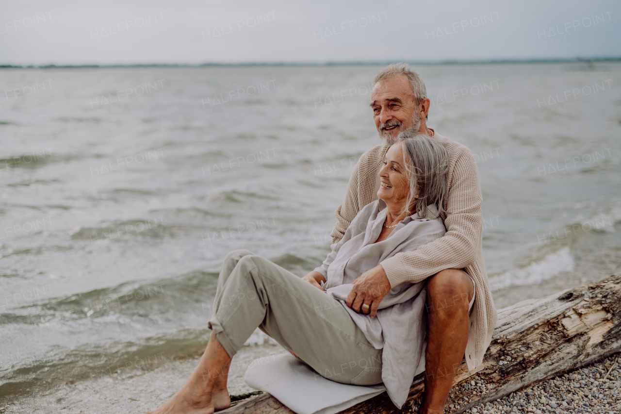 Senior couple sitting and having romantic moment at the autumn sea.