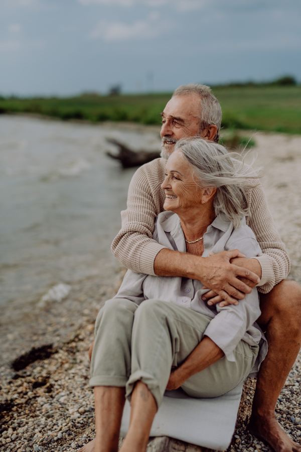 Senior couple sitting and having romantic moment at the autumn sea.