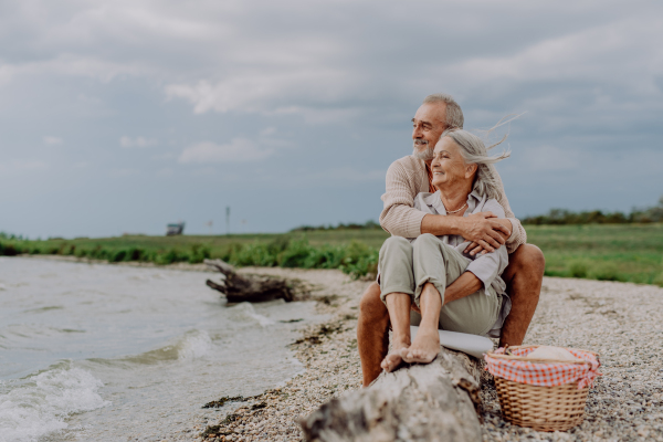 Senior couple sitting and having romantic moment at the autumn sea.