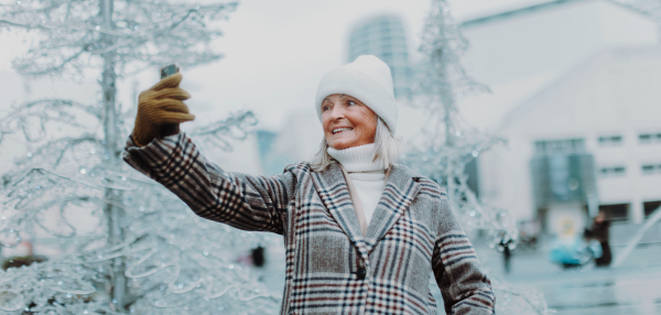 Elegant senior woman taking selfie, during winter christmas day. Winter banner with copy space.