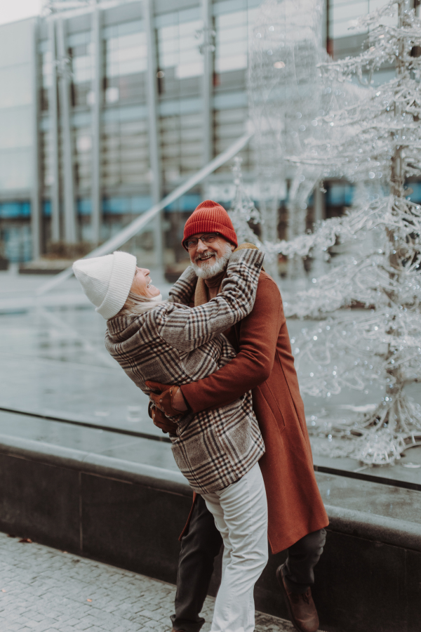 Portrait of seniors in winter at outdoor ice skating rink. Smiling, embracing each other.