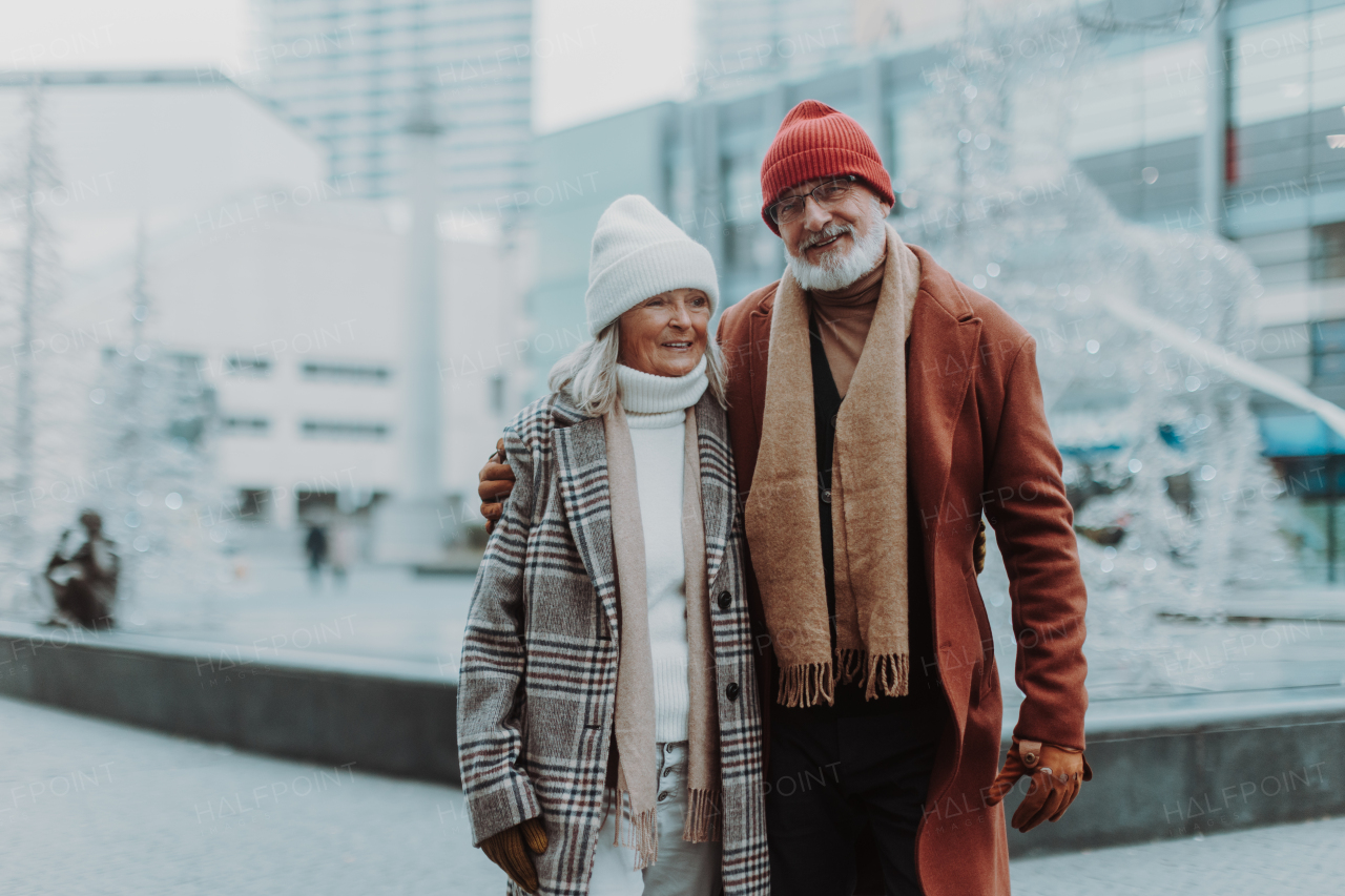 Portrait of seniors in winter at an outdoor ice skating rink. Beautiful elderly woman and man in the city during Christmas day.