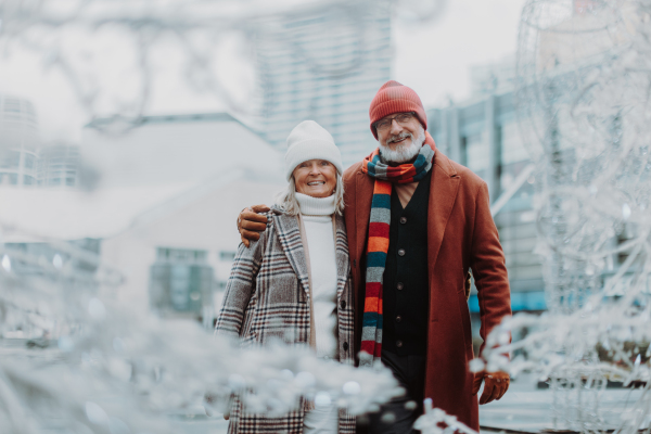 Elegant senior couple walking near a river, during cold winter day.