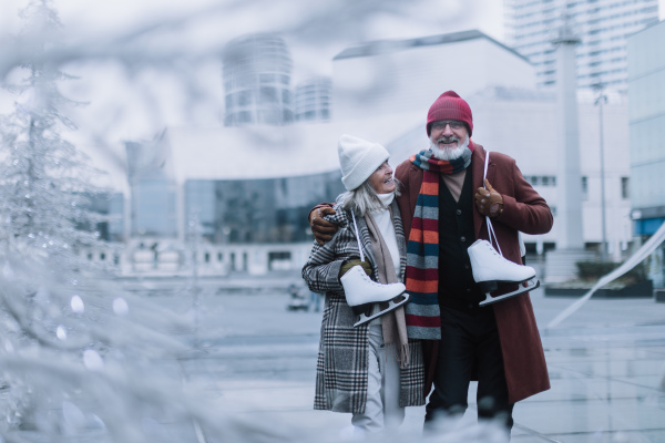 Portrait of seniors with ice skates at outdoor ice skating rink at the winter. Laughing, embracing each other.