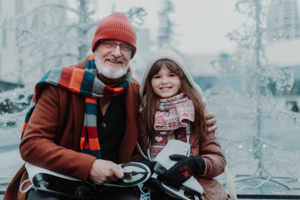 Portrait of grandfather and granddaughter in winter at an outdoor ice skating rink.