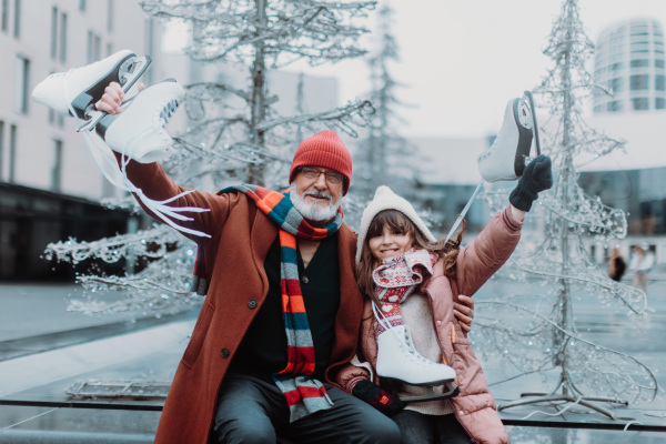 Portrait of grandfather and granddaughter in winter at an outdoor ice skating rink.