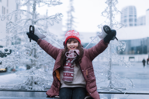 Portrait of cute girl at outdoor ice skating rink looking forward to going ice skating. Winter fun during the Christmas holidays.