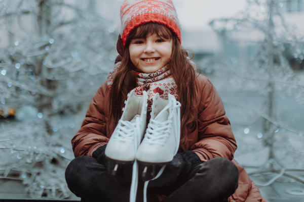 Portrait of cute girl at outdoor ice skating rink looking forward to going ice skating. Winter fun during the Christmas holidays.