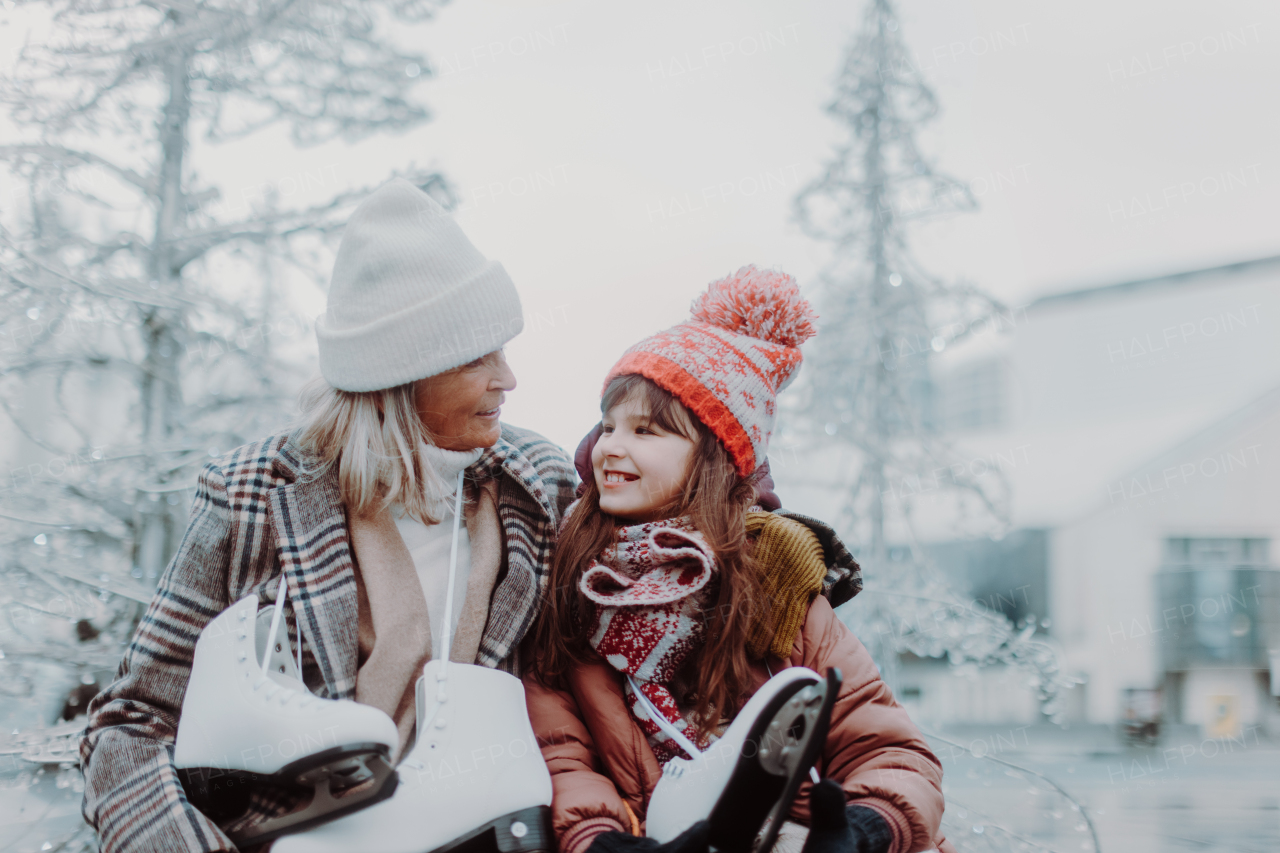 Portrait of grandmother and granddaughter in winter at an outdoor ice skating rink.