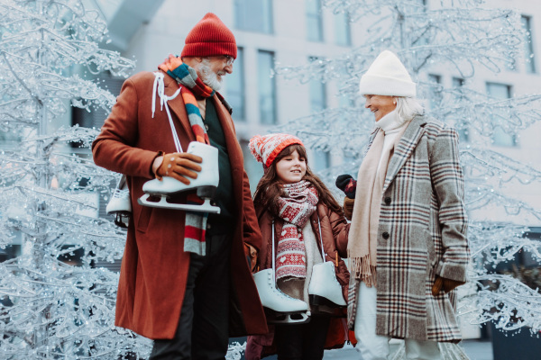 Seniors with their granddaughter in a winter at outdoor ice skating rink.