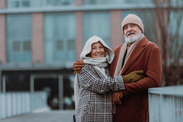 Elegant senior couple walking near a river, during cold winter day.